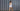 Woman in a white dress walking past a gray corrugated metal wall.