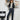 Petite woman holding a guitar with a 'Hey, Joanie' chair in the background with skinny jeans 
