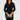 Woman wearing a black dress holding a clutch against a plain background